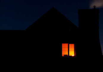 Light from the window of the house in the dark evening time.