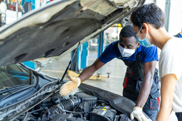 An auto mechanic talking to female customer in garage