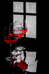 Still life with glasses and red wine against the background of a window silhouette