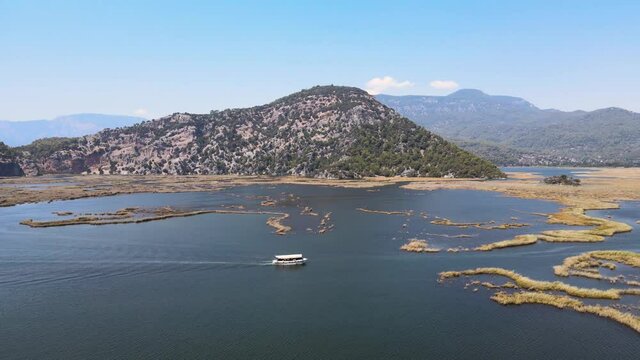 Filming from a drone of a pleasure boat against the background of a green mountain frame in Turkey, the city of Dalyan Turtle Coast Iztuzu