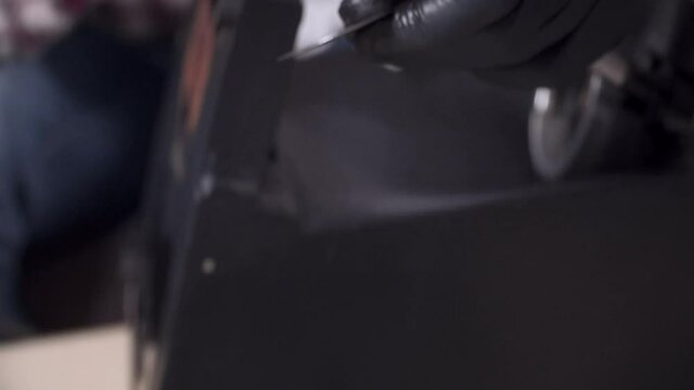 A young man is trying to fix his own kitchen appliances at home, a coffee maker. Caucasian male repairs a coffee machine with a screwdriver dressed in a plaid shirt and safety glasses and gloves