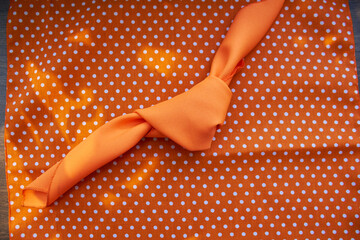 orange napkin and bow tie with a knot and orange cloth with soft balls and circles