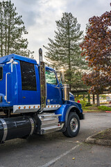 Big rig blue semi truck tractor with back compartment for truck driver rest standing on the parking lot in sunshine