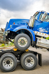 Big rig semi truck towing another blue semi truck tractor on the chassis frame