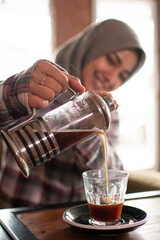 asian female pour coffee into a cup in a cafe