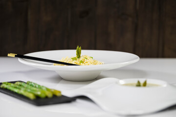 Select focus of a delicious looking plate of pasta and asparagus with out of focus dishes