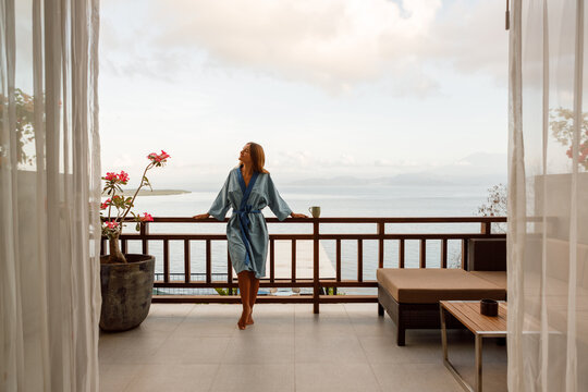 The girl is standing on a terraced house by the sea, enjoy morning fresha air with ocean view