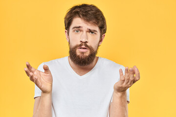 Bearded man emotions gestures with hands facial expression white t-shirt yellow background