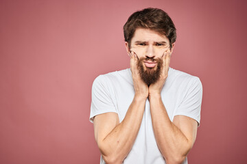 Emotional bearded man in white T-shirt discontent pink background