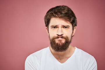 Obraz premium Emotional bearded man in white T-shirt discontent pink background