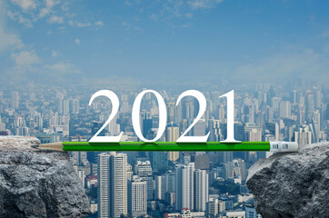 2021 white text with green pencil on rock over modern city tower, office building and skyscraper, Business success strategy planning concept, Happy new year 2021 calendar cover