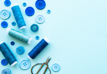 Spools of thread and buttons in blue tones on a blue background