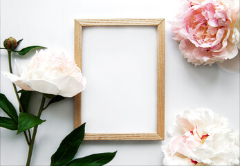 Wooden frame surrounded by beautiful pink peonies on a white background
