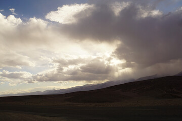 Moody landscape view of sun beams and rays breaking through storm clouds over Death Valley