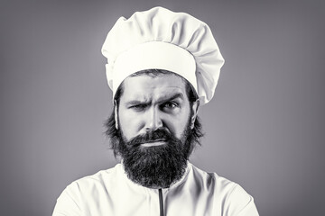 Portrait of a serious chef cook. Confident bearded male chef in white uniform. Serious cook in...