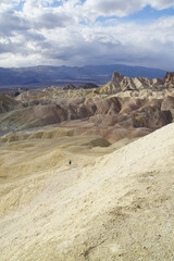 A hiker in the distance, exploring the badlands terrain, as seen from Zabriskie Point in Death Valley National Park