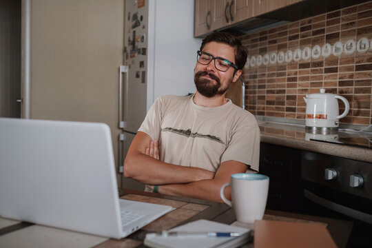 Smiling Hipster Freelancer Holding Hands Behind Head Sitting At Office Desk Behind Laptop.