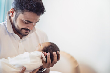 Closeup portrait of young asian Indian father holding his newborn baby with copy space. Healthcare...