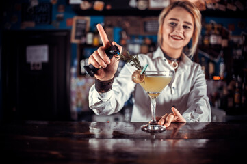 Girl barman formulates a cocktail on the taproom