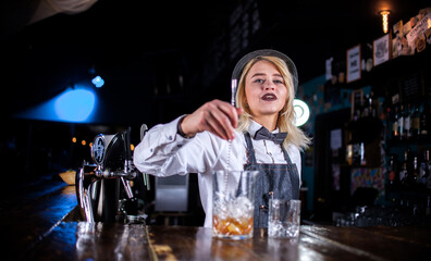 Girl barman creates a cocktail behind the bar