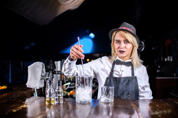 Portrait of woman bartending makes a cocktail behind the bar