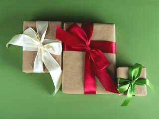 Beautiful packaging of presents with multicolor satin ribbons, craft paper on the green background.