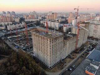Fototapeta premium Aerial view construction of a high-rise business center in the big city. Beautiful panoramic landscape of the city at dawn from a height.