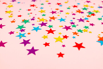 multicolored backdrop of colored stars confetti on a pink background
