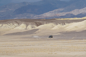 Scenic landscape view of a jeep driving in Death Valley, on a stormy and cloudy day