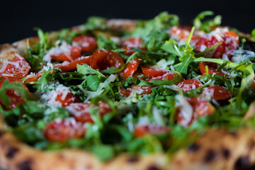 Close up of gourmet pizza with tomatoes, salad and cheese