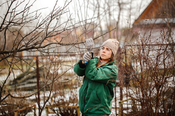 Caucasian cute woman gardener with garden tool close up, gardener pruning branches with pruning...