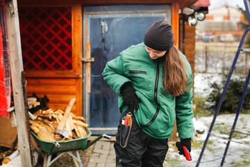 Caucasian cute woman gardener with garden tool close up, gardener pruning branches with pruning shears, winter plant pruning, winter gardening work in winter work clothes