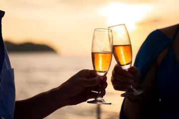 Hand holding a glass drinking wine on Sunset sea background.