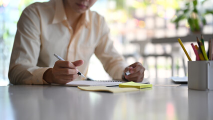 Cropped shot of a businessman is signing or writing on white paper using a fountain pen.
