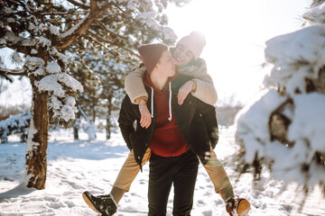 Fototapeta na wymiar Happy Couple in love walking and having fun in snow forest. Young man and woman playing in the snow on winter holidays. Christmas, New year. Winter lifestyle.