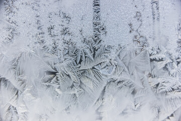 Texture of blue frost on a glass window. Frosty cold weather. White ice patterns texture close-up....