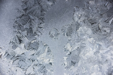 Fototapeta premium Texture of blue frost on a glass window. Frosty cold weather. White ice patterns texture close-up. New year and Christmas background