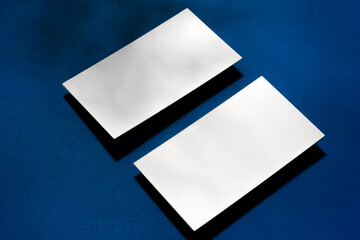 Two stacks of blank businesscards on blue background