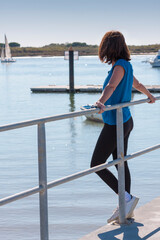 beautiful young girl leaning on the railing of a pier looking to the horizon