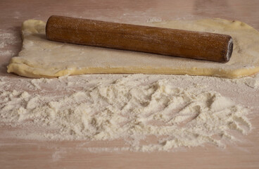 Fototapeta na wymiar Roll out the dough with a rolling pin on the table. Cooking.