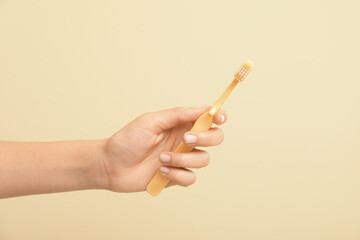 Female hand with toothbrush on color background