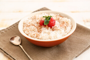 Bowl of tasty rice pudding with cherry on napkin