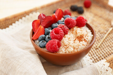 Bowl of tasty rice pudding with berries on wicker tray