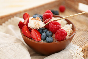Bowl of tasty rice pudding with berries on wicker tray