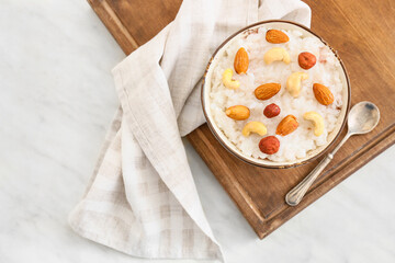 Bowl of tasty rice pudding with nuts on wooden board