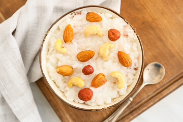 Bowl of tasty rice pudding with nuts on wooden board