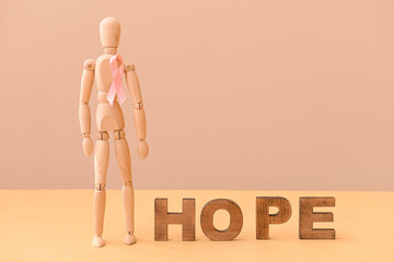 Mannequin with pink ribbon and word HOPE on color background