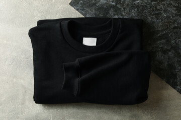 Black folded sweatshirt on two tone background