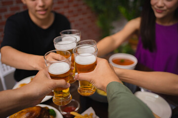 Close-up of a group of Asians holding a beer glass they clink glasses beer.