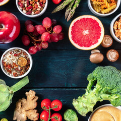 Organic vegan food square design template with fruit and vegetables, legumes, mushrooms etc, shot from the top with a place for text on a dark blue wooden background